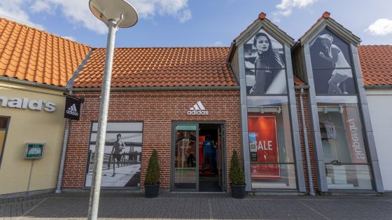 Kvinde iført adidas sportstop og træningstights som løfter håndvægte – inspiration til træning og stil fra adidas outlet i Ringsted Designer Outlet