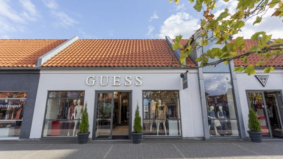 Kvinde og mand kigger i kameraet, iklædt Guess tøj. Inspirationsbillede til at købe Guess tøj og overtøj i Ringsted Designer Outlet.