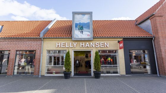 Dreng iklædt lyse bukser, hvid t-shirt og mørkeblå trøje kigger i kameraet. Inspirationsbillede til at købe Helly Hansen tøj i Ringsted Designer Outlet.