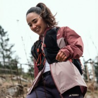 Kvinde iført outdoor tøj fra Adidas - en vinsjakke og trackpants samt en rygsæk - inspiration til outdoortøj fra adidas outlet i Ringsted Designer Outlet