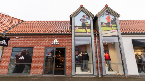 Kvinde iført outdoor tøj fra Adidas - en vinsjakke og trackpants samt en rygsæk - inspiration til outdoortøj fra adidas outlet i Ringsted Designer Outlet