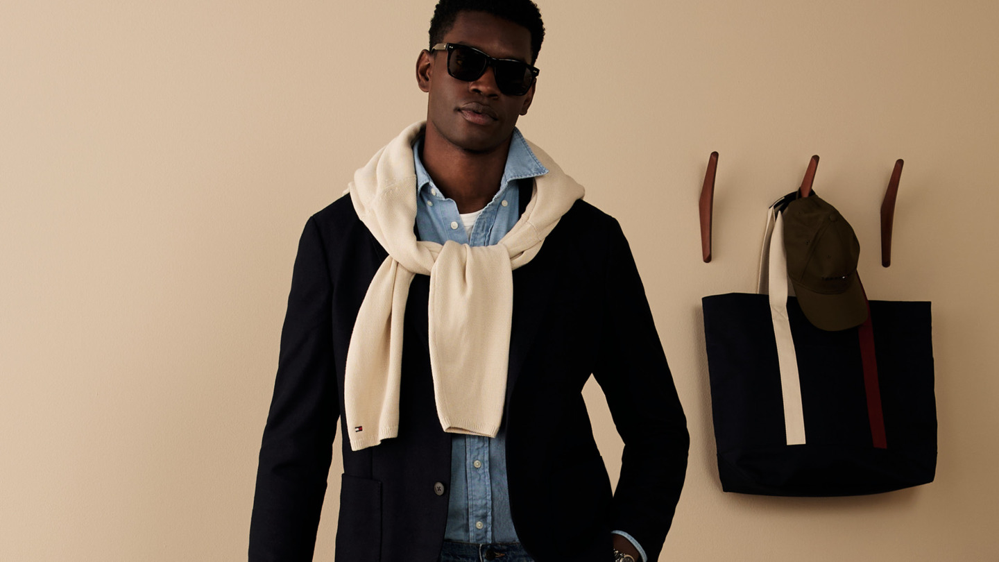 Mand iført tøj fra Tommy Hilfiger - en blå skjorte, en hvid strik og en blazer samt sol briller - inspirationsbillede for Tommy Hilfiger Outlet i Ringsted Designer Outlet