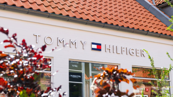 Modeller iført klassisk sommerligt Tommy Hilfiger-outfit på en båd – topbanner på Tommy Hilfiger outlets brandside hos Ringsted Designer Outlet