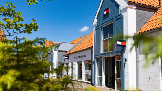 Mand iført tøj fra Tommy Hilfiger - en blå skjorte, en hvid strik og en blazer samt sol briller - inspirationsbillede for Tommy Hilfiger Outlet i Ringsted Designer Outlet